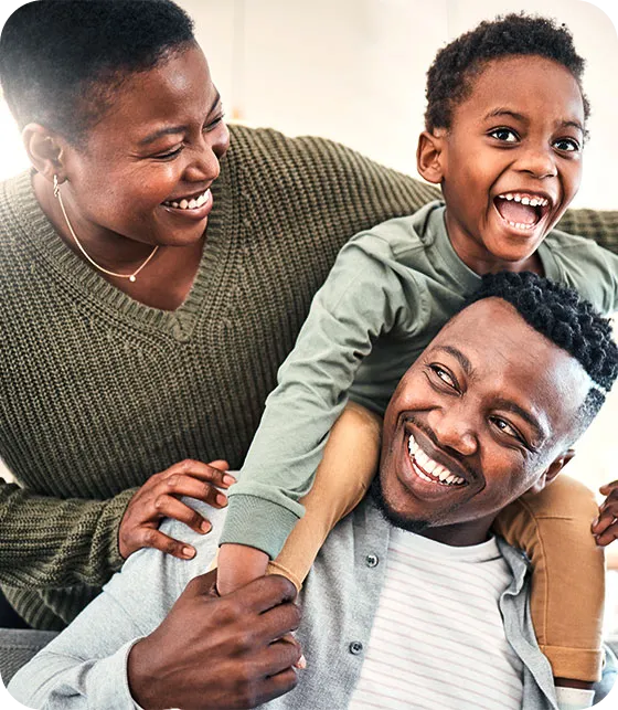 Família negra feliz; pai, mãe e filho sorrindo.